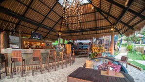 An outdoor seating area with wooden furniture and a thatched roof.