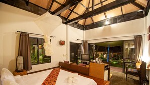 Camera d'albergo con un letto grande, una televisione, una scrivania e vista sul giardino.