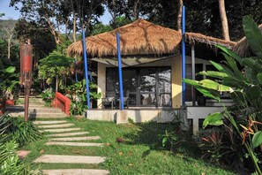 A thatched-roof structure with a covered seating area, surrounded by lush greenery and a stone pathway. - Lalaanta Hideaway Resort (Ko Lanta)