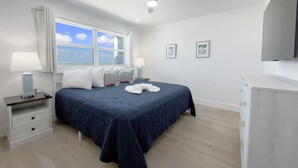 A bedroom with a bed, a nightstand, a desk, a ceiling fan, and a window with a view. - Gateway Villas #899 "Sunset Beach Penthouse" (Fort Myers Beach)
