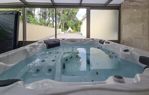 Ein Whirlpool mit Blick auf einen Garten und ein Gebäude im Hintergrund.