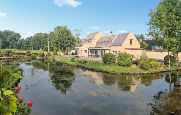 Ein Haus mit Teich, umgeben von Grün und Bäumen.