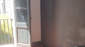 Een slaapkamer met een bed, een vloerkleed en een deur naar buiten.