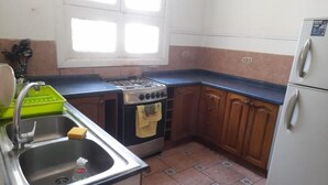 Een keuken met een spoelbak, fornuis en koelkast.