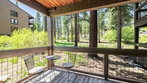A wooden deck with two chairs and a small table, overlooking a forested area. - Northstar Studio near village and slopes (Truckee)