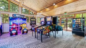 An indoor arcade with various gaming machines, including racing and fighting games, and a vending machine. - Northstar Studio near village and slopes (Truckee)