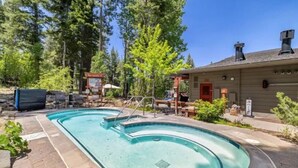 A swimming pool with a stone deck, surrounded by trees and a building with a red door. - Northstar Studio near village and slopes (Truckee)