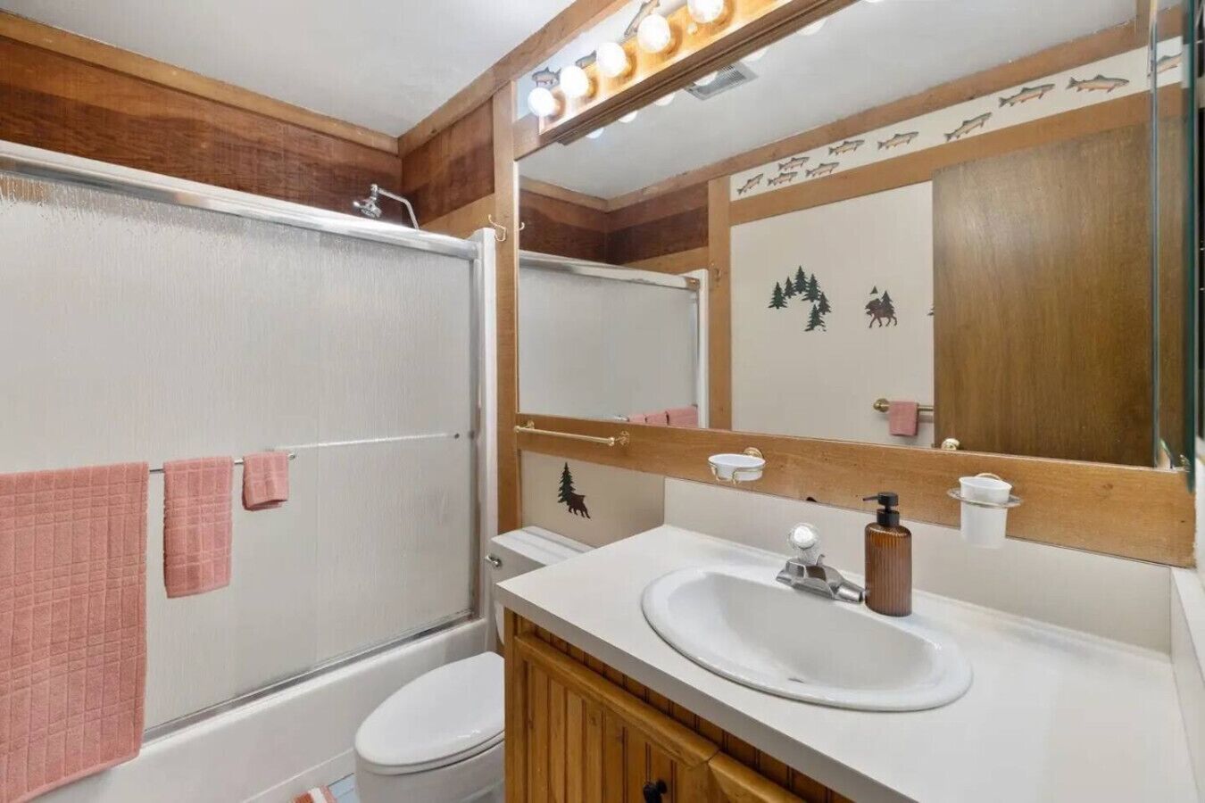 Un baño con ducha, inodoro, lavabo y espejo.