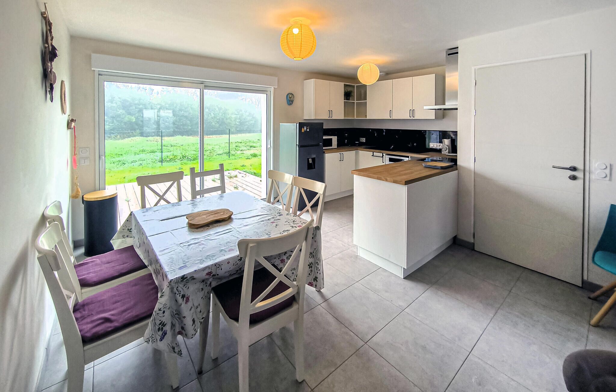 Una cocina moderna con armarios blancos, encimera de madera y un comedor con mesa y sillas.