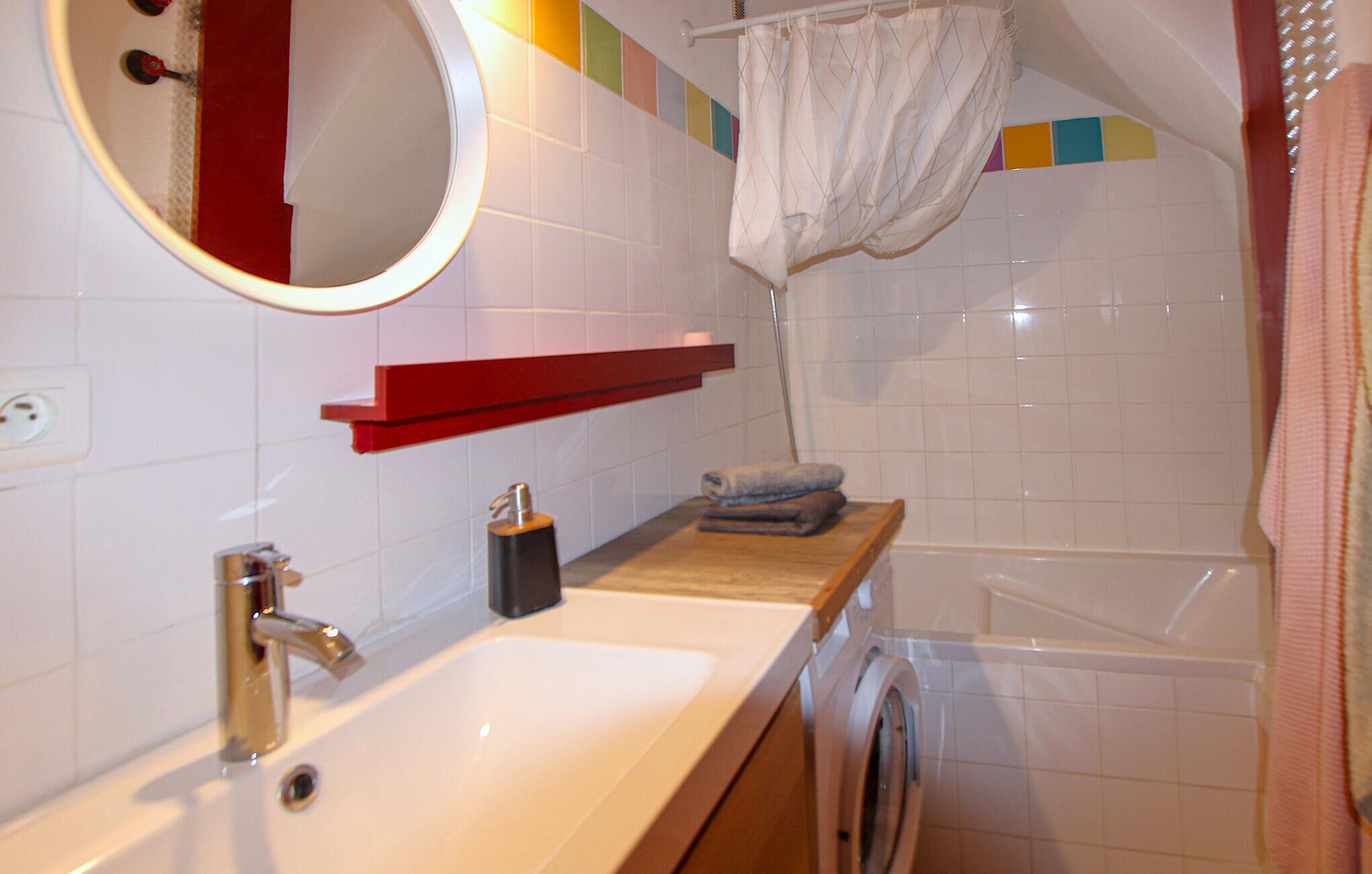 A bathroom with a sink, mirror, towel rack, and a shower area.