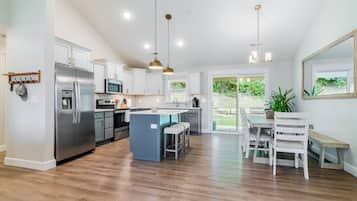 A modern kitchen with stainless steel appliances, a central island, and pendant lighting.