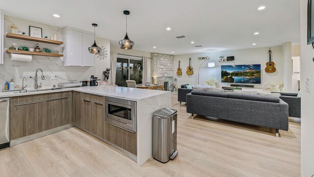 Een moderne keuken met een centraal eiland, inbouwapparatuur en hanglampen.