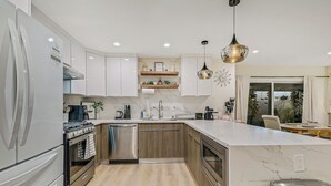Een moderne keuken met witte kasten, roestvrijstalen apparatuur en een marmeren aanrecht.