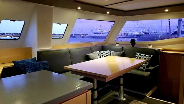 L'intérieur d'un bateau comprend un espace repas, des sièges et de grandes fenêtres offrant une vue sur le port de plaisance.