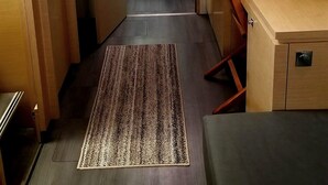 Un intérieur moderne et compact, avec des meubles en bois, un petit coin cuisine et une porte vitrée donnant sur un espace extérieur.