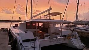 Un yacht blanc baptisé « Salty Britches » était amarré dans une marina, avec un coucher de soleil en toile de fond.