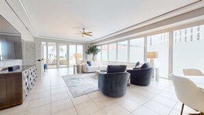 A spacious living room with a large TV, comfortable seating, and a view of the outdoors. - Exclusive Gulf view 3BR, pool & tennis (Miramar Beach)