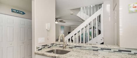 A modern kitchen with a granite countertop, stainless steel sink, and a built-in dishwasher.