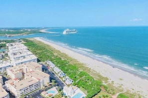 A coastal hotel with a beachfront view, a swimming pool, and a parking area. - Seaport Sands Townhome l Private Beach Access (Cape Canaveral)