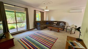 Ein Wohnzimmer mit Ecksofa, Couchtisch, Streifen Teppich und einer Lampe.