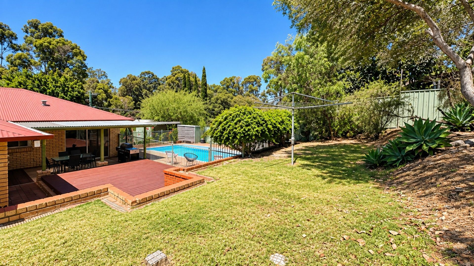 A backyard with a swimming pool, a barbecue area, and a covered patio.