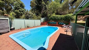 Ein rechteckiger Swimmingpool mit blauer Innenseite, umgeben von einer Ziegelterrasse.
