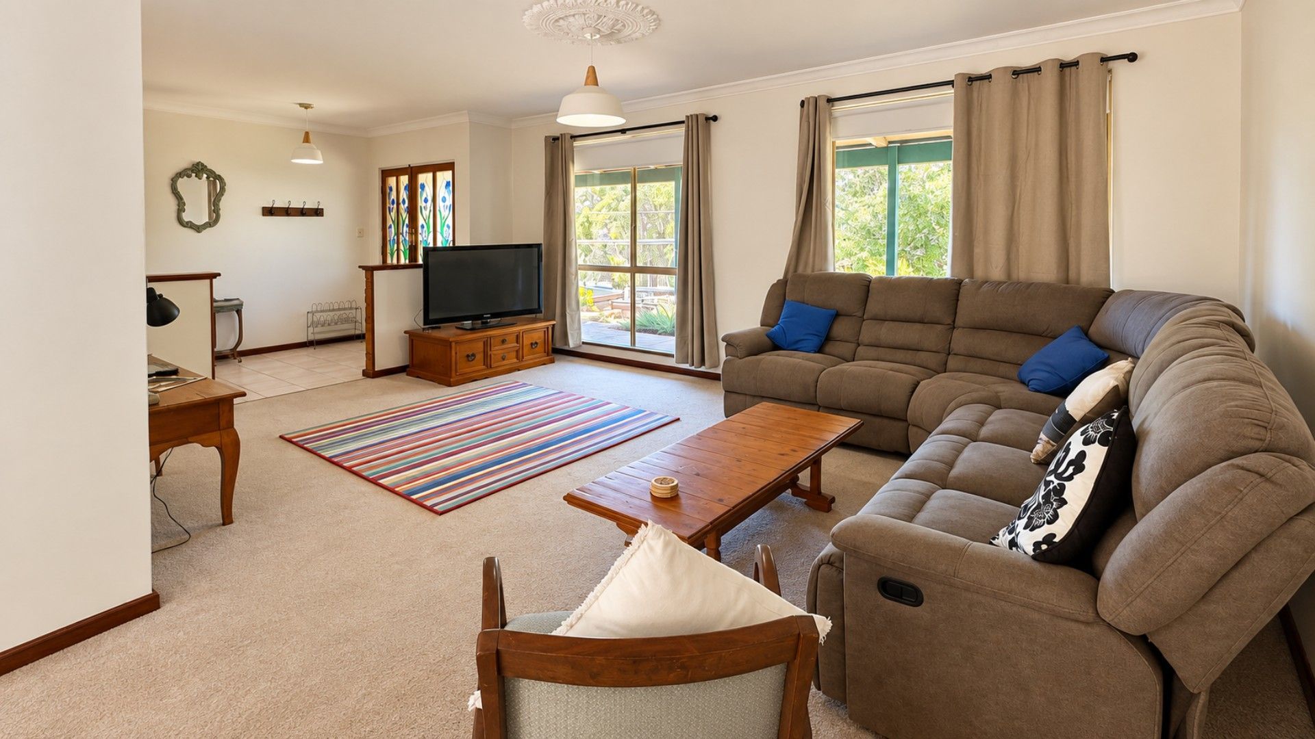 A living room with a sofa, a coffee table, a TV, and a window with curtains.