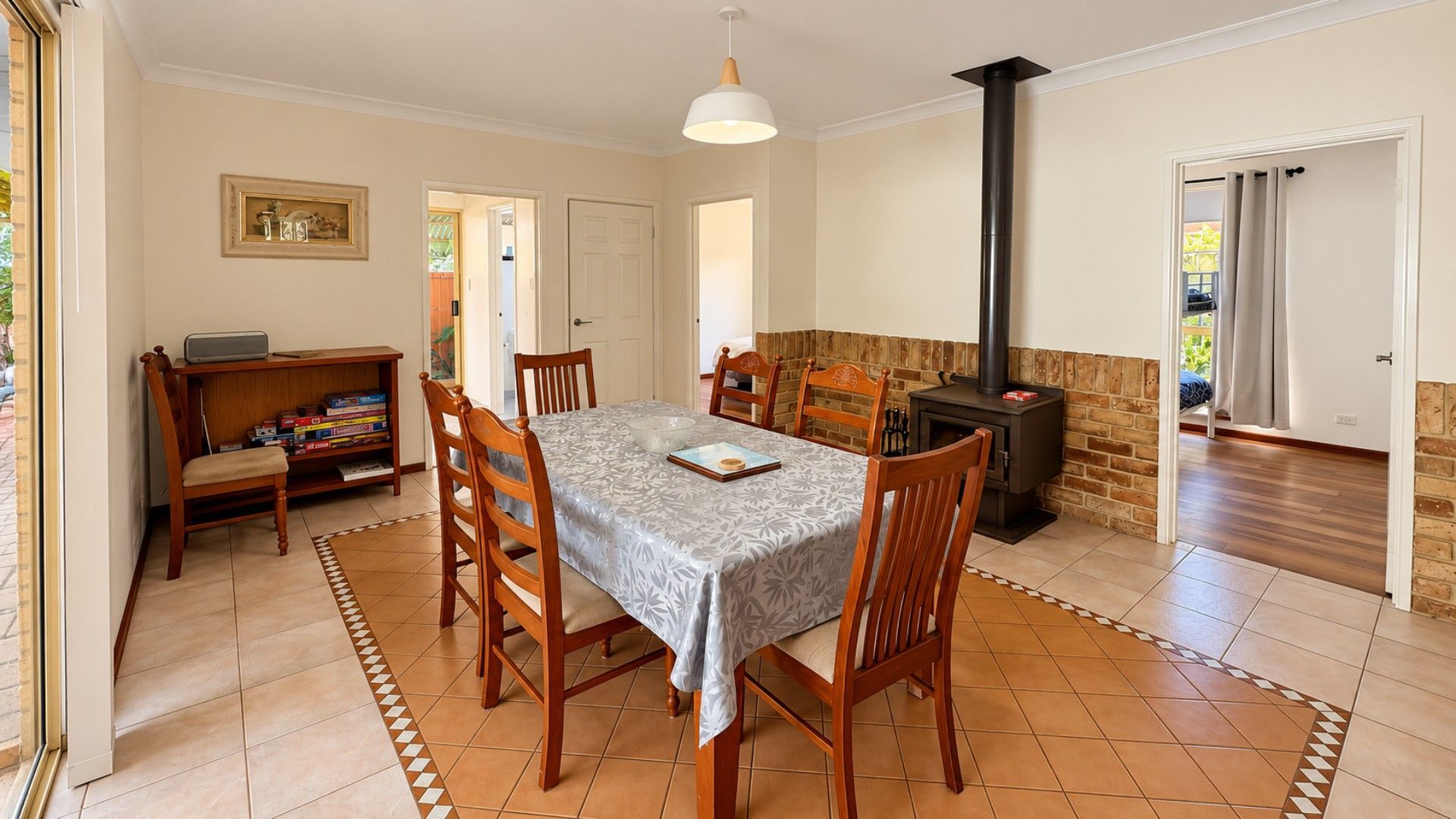 A dining area with a table, chairs, a bookshelf, and a fireplace.