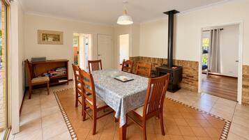 A dining area with a table, chairs, a bookshelf, and a fireplace.