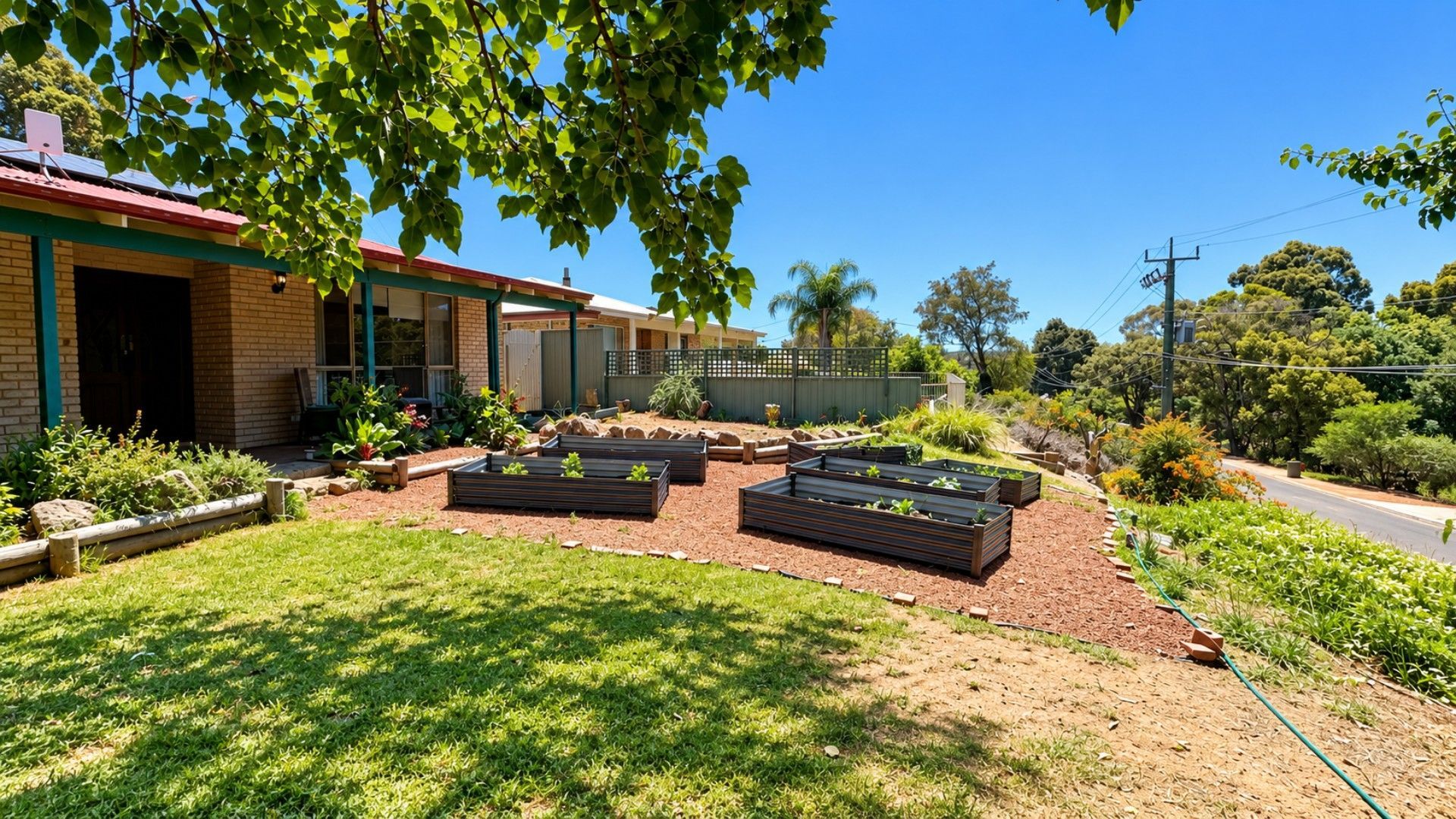 A residential property with a garden, outdoor seating area, and a brick house with a red roof.