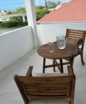 A wooden table and chairs on a balcony with a tiled floor, a pitcher of water, and a glass on the table. - Lovely townhouse near Oistins and Miami Beach (Christ Church)