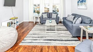 Ein modernes Wohnzimmer mit grauem Sofa, Couchtisch und Bücherregal.