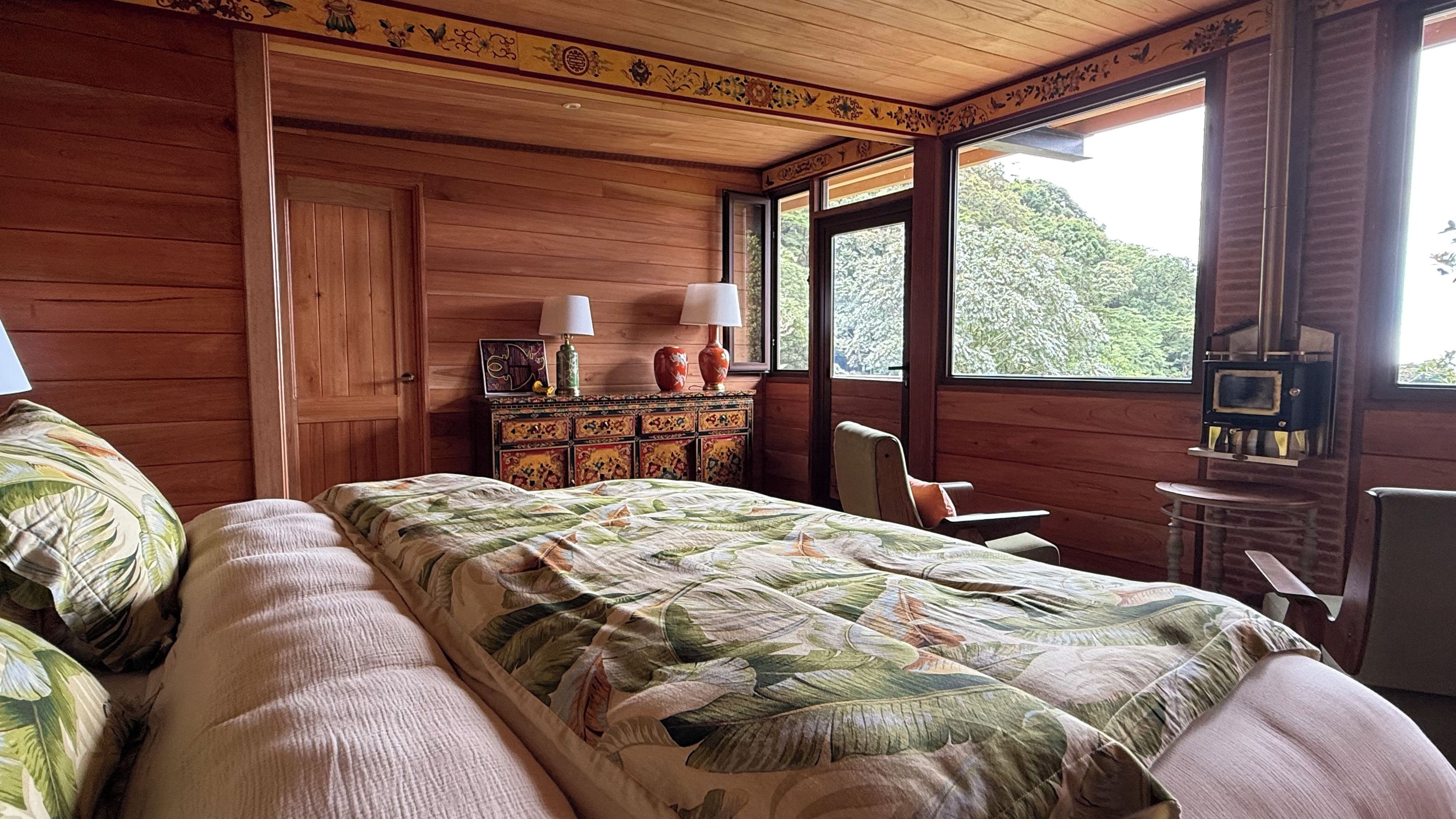 A wooden cabin bedroom with a bed, dresser, and a fireplace.
