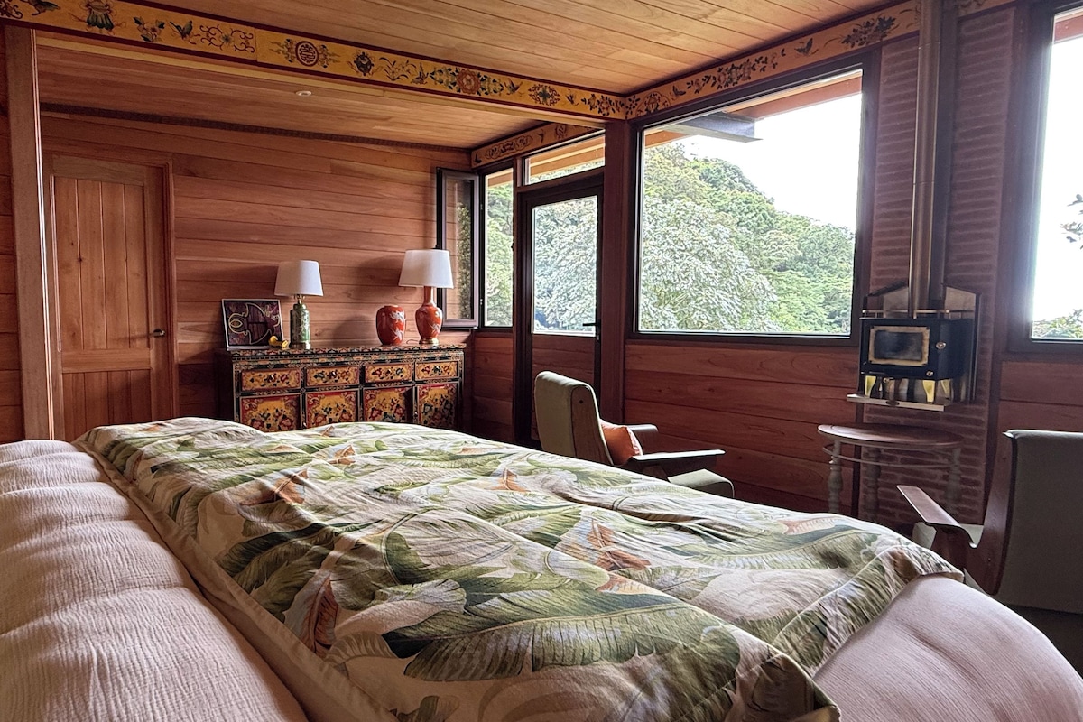Un dormitorio de cabaña de madera con cama, cómoda y chimenea.