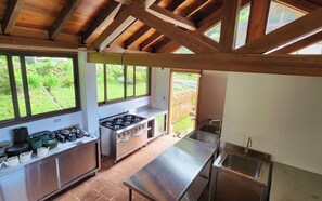 A kitchen with a gas stove, sink, and large windows. - Wild on the Farm, Boquete Cloud Forest Lodge (Los Naranjos)