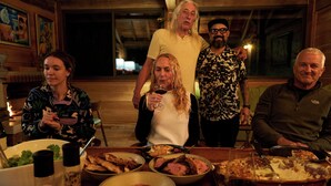 A group of people around a dining table with food and drinks.