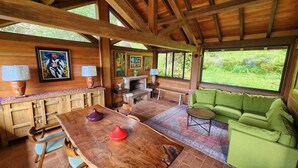 A wooden interior with a dining table, chairs, a green sofa, and a fireplace.