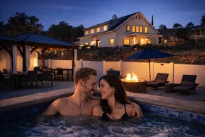 Ein Paar in einer Whirlwanne, im Hintergrund ein Haus und eine Terrasse.
