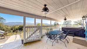 A covered patio with a table and chairs, a ceiling fan, and a view of the mountains.