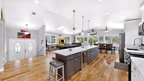 Una cocina amplia con una isla grande, suelo de madera y un comedor con sillas y mesa.