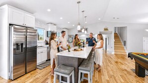 Una cocina moderna con electrodomésticos de acero inoxidable, una isla de mármol y una mesa de billar.