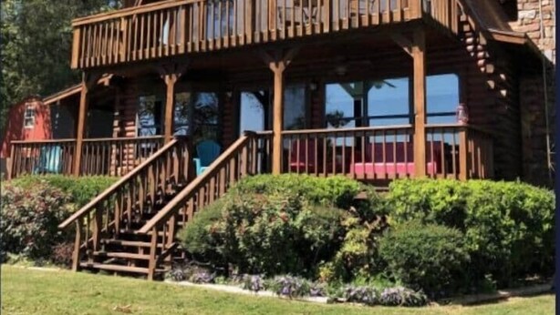 A two-story log cabin with a balcony and a stone chimney. - Callender Blue, a cozy lakeside cabin paradise (Callender Lake)
