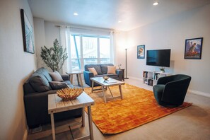 A living room with a sofa, coffee table, and TV. - Meridian Suite at North Star Lodge • HotTub • View (Anchorage)