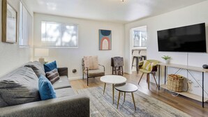 Una sala de estar moderna con un sofá, dos sillones, una mesa de centro y un televisor montado en la pared.