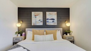 Un dormitorio moderno con una cama grande, dos mesitas de noche y arte abstracto en la pared.