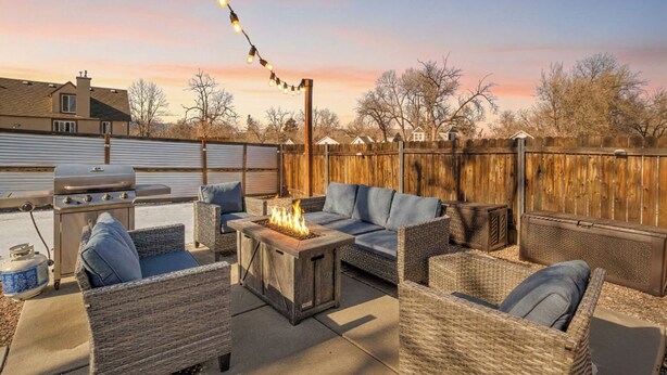 Un patio al aire libre con mobiliario de mimbre, una chimenea y una parrilla de barbacoa.