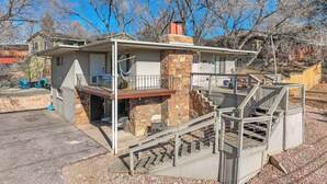 A two-story house with a stone chimney, a balcony, and a staircase leading to the upper floor. - Ivywild Flat! Pet Friendly Near Broadmoor w/ Views (Colorado Springs)