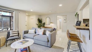 A modern living room with a grey sofa, a round coffee table, and a bar area with stools. - Ivywild Flat! Pet Friendly Near Broadmoor w/ Views (Colorado Springs)