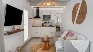 Una cocina moderna con armarios blancos, techo de madera y una lámpara colgante.