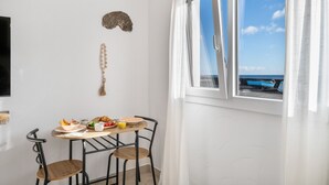 En matplats med ett bord, stolar och utsikt över havet genom ett fönster.